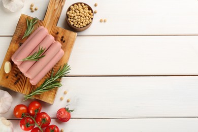 Photo of Fresh raw vegetarian sausages and vegetables on white wooden table, flat lay. Space for text
