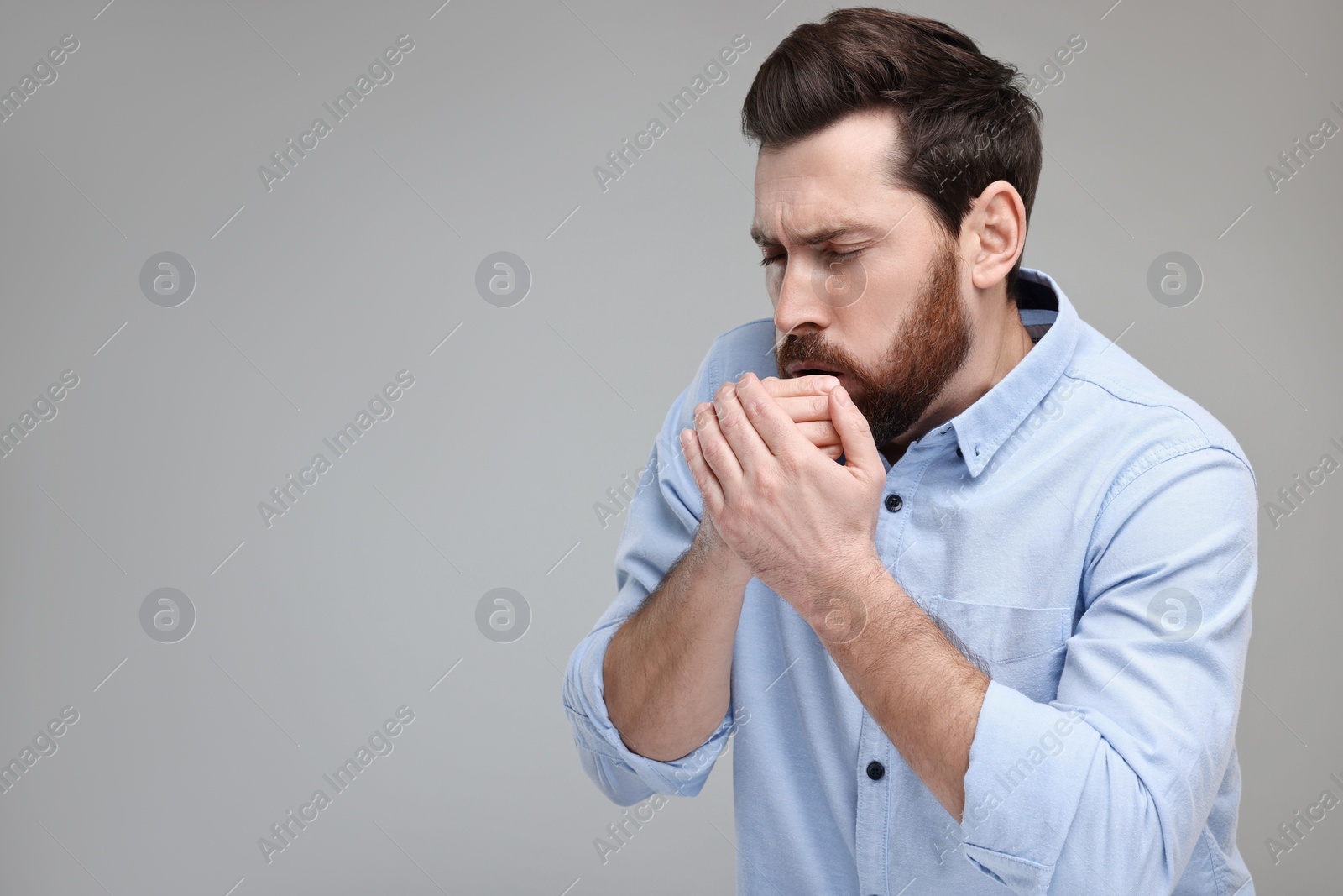 Photo of Sick man coughing on light grey background, space for text. Cold symptoms