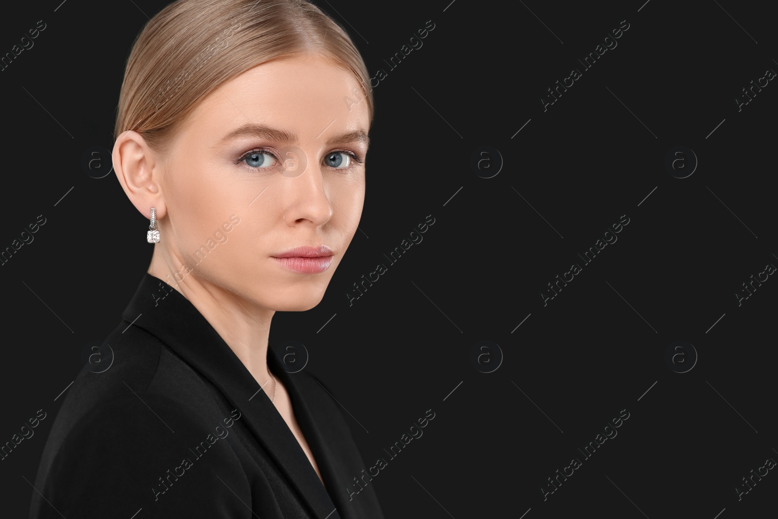 Photo of Beautiful young woman with elegant earrings on black background, space for text