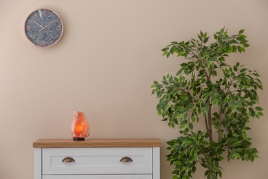 Himalayan salt lamp on cabinet against light wall