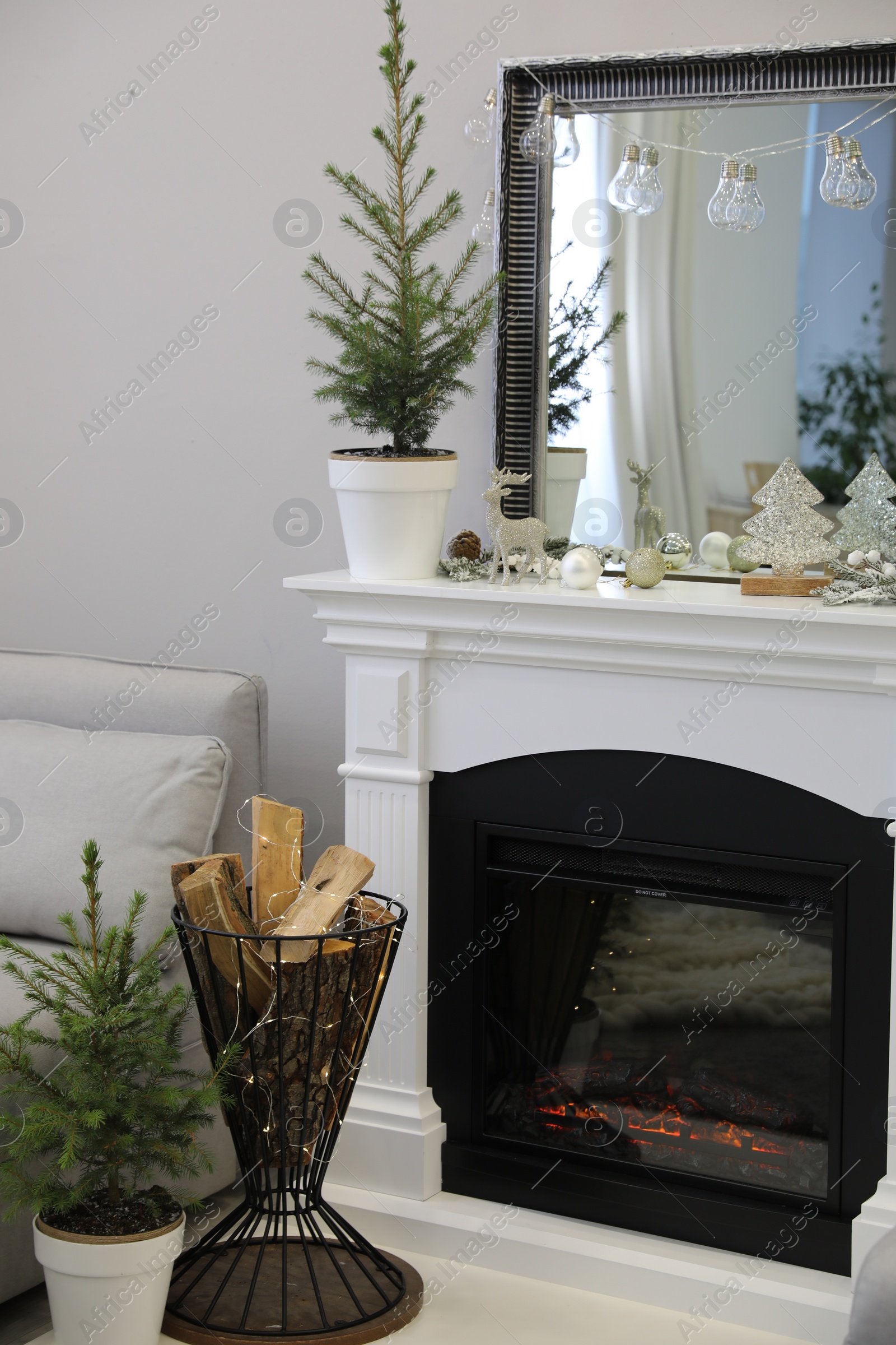 Photo of Little fir tree and Christmas decorations in room with fireplace. Stylish interior design