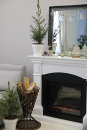Photo of Little fir tree and Christmas decorations in room with fireplace. Stylish interior design