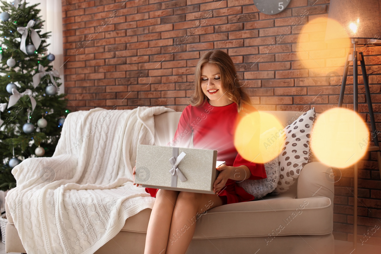 Photo of Beautiful young woman opening gift box at home. Christmas celebration