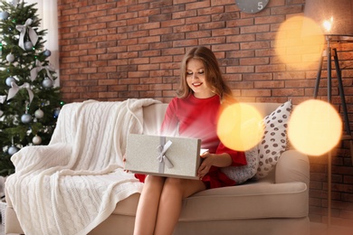 Photo of Beautiful young woman opening gift box at home. Christmas celebration