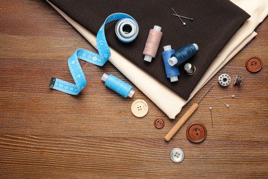 Photo of Flat lay composition with different sewing accessories on wooden background