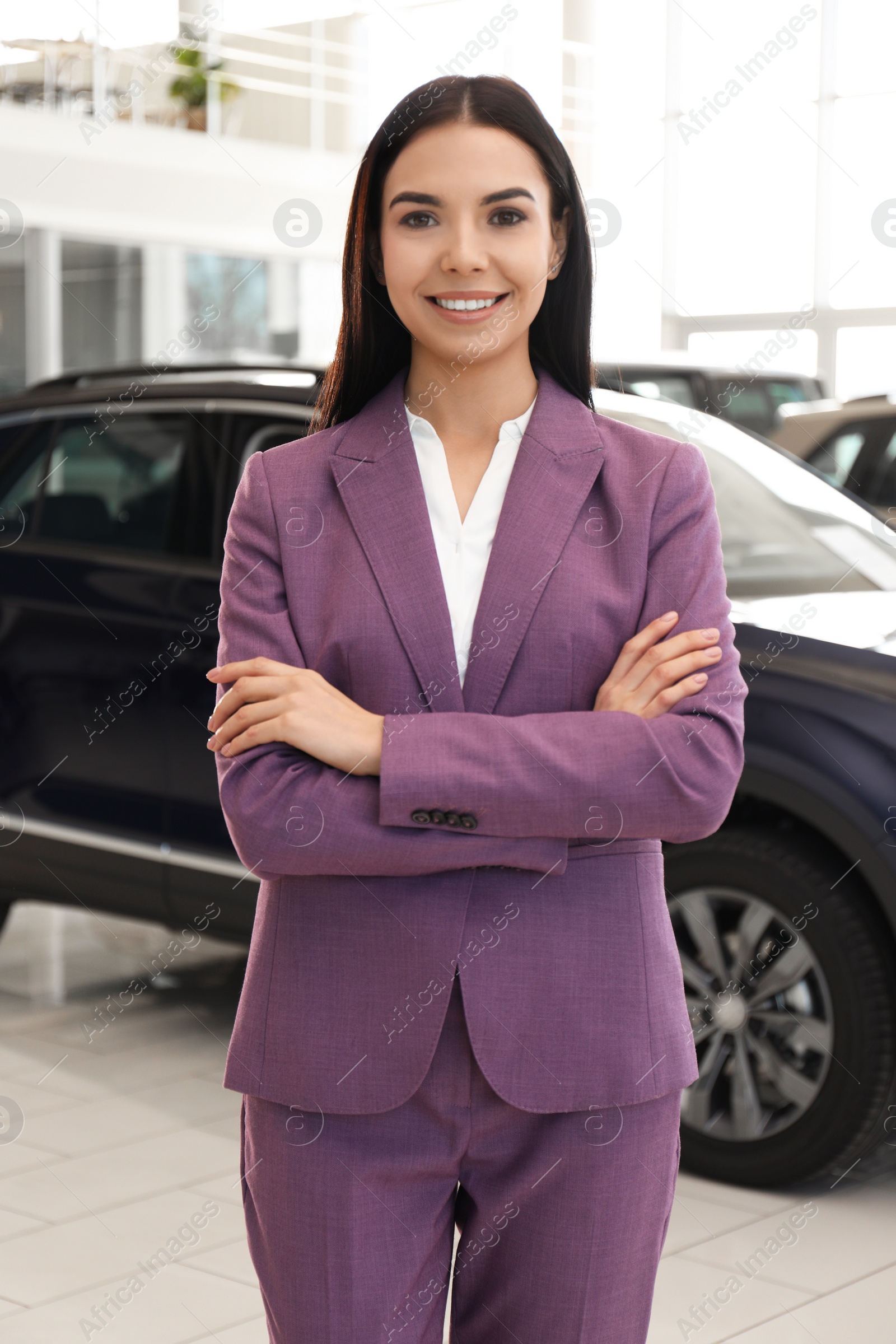 Photo of Happy young saleswoman in modern car salon