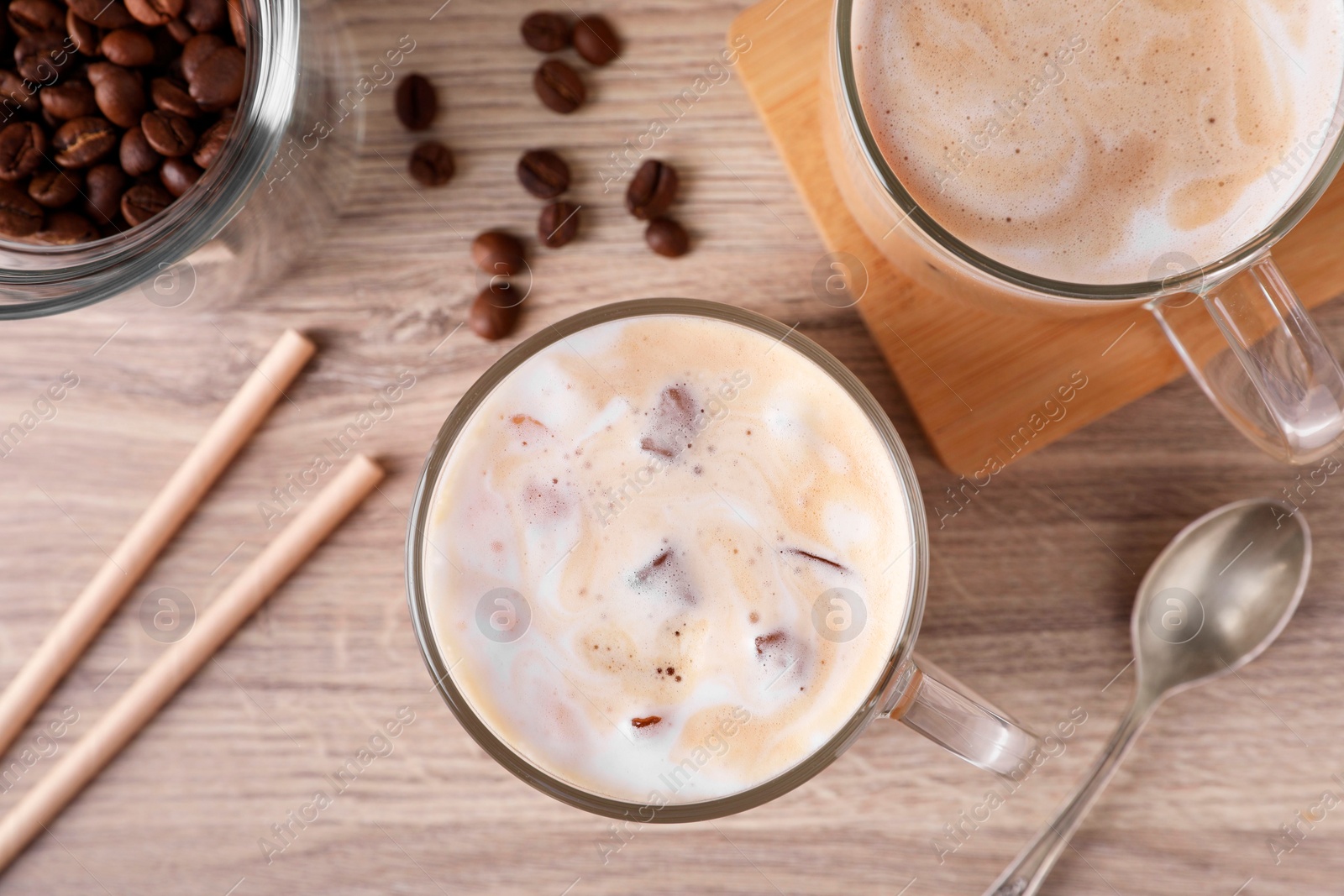 Photo of Fresh iced coffee and beans on wooden table, flat lay