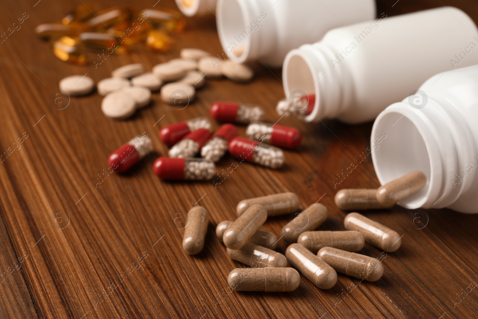 Photo of Overturned bottles with different dietary supplements on wooden table, closeup