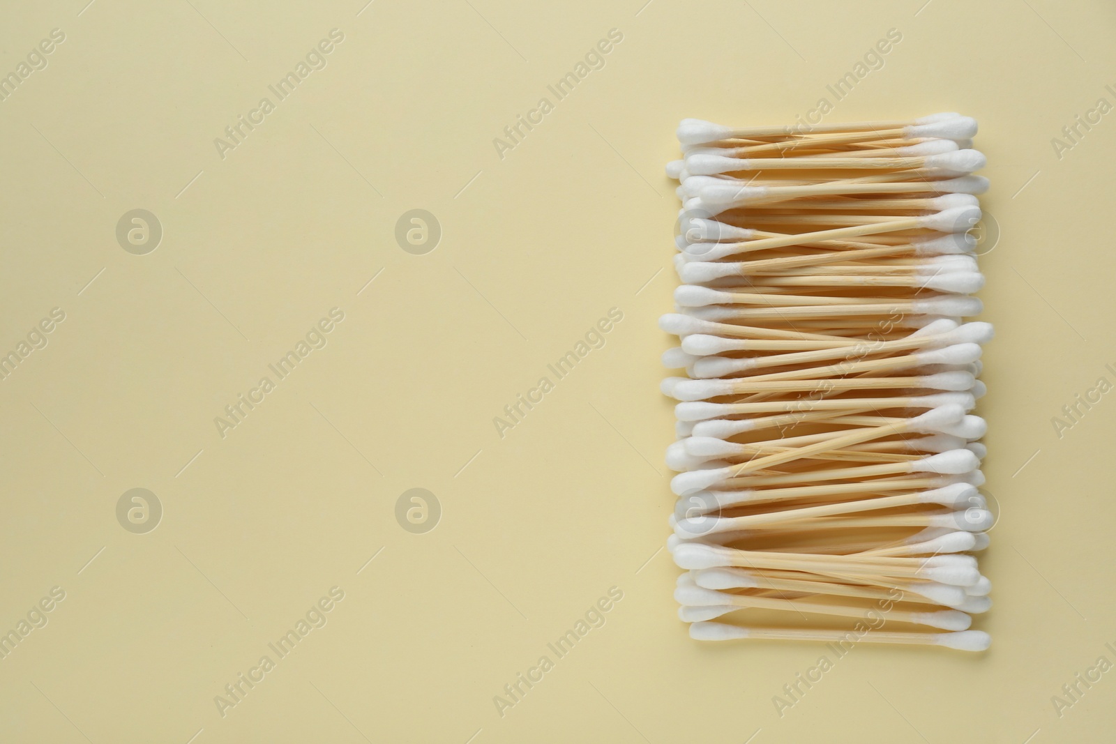 Photo of Many wooden cotton buds on beige background, flat lay. Space for text