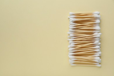 Photo of Many wooden cotton buds on beige background, flat lay. Space for text