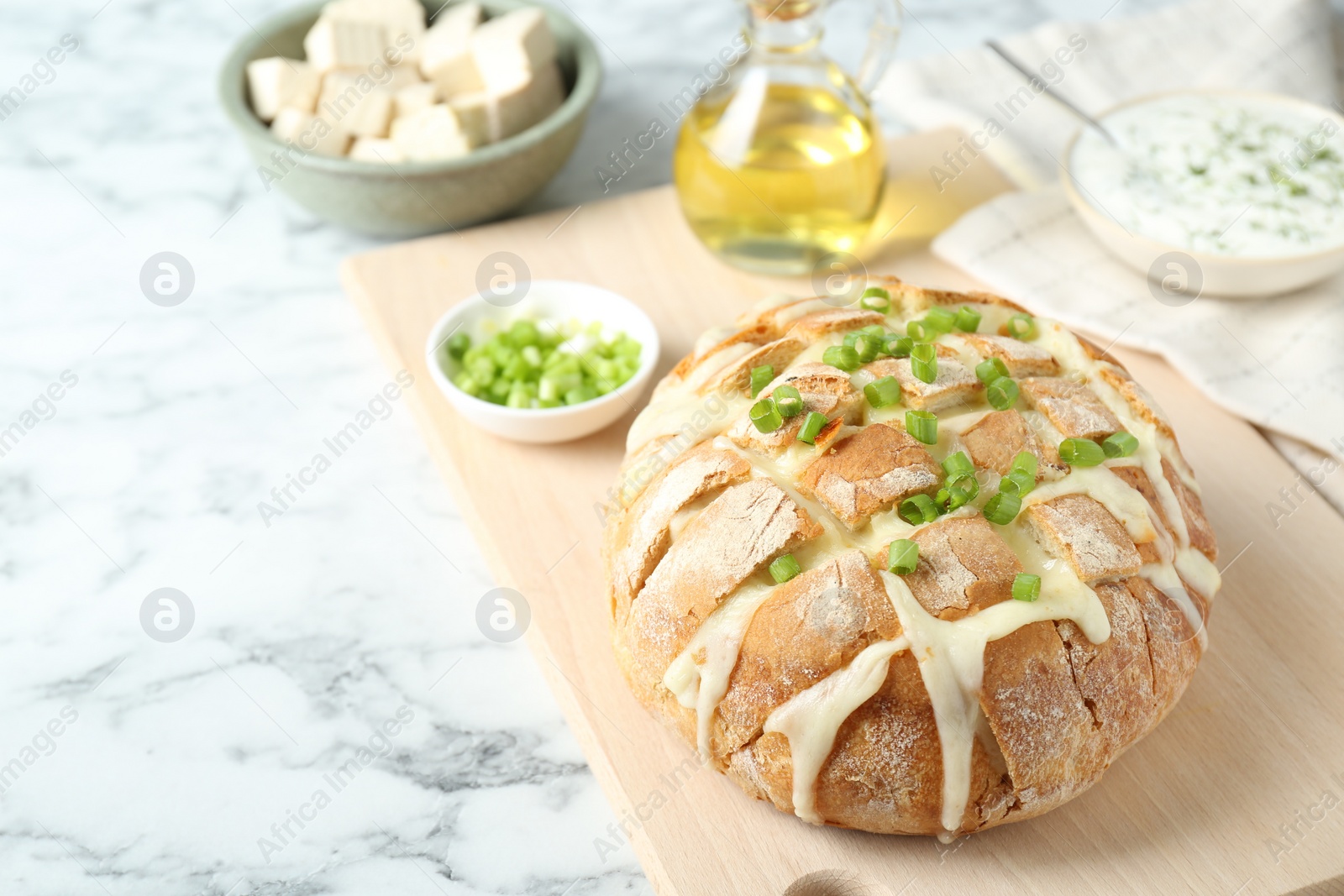 Photo of Freshly baked bread with tofu cheese and green onion on white marble table. Space for text