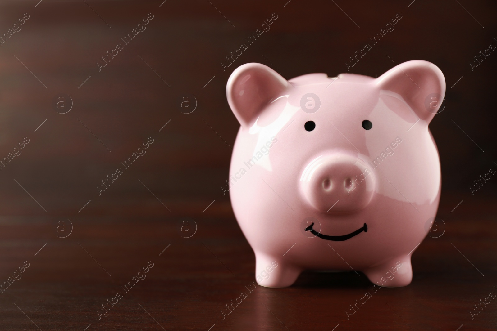 Photo of Ceramic piggy bank on wooden table. Space for text