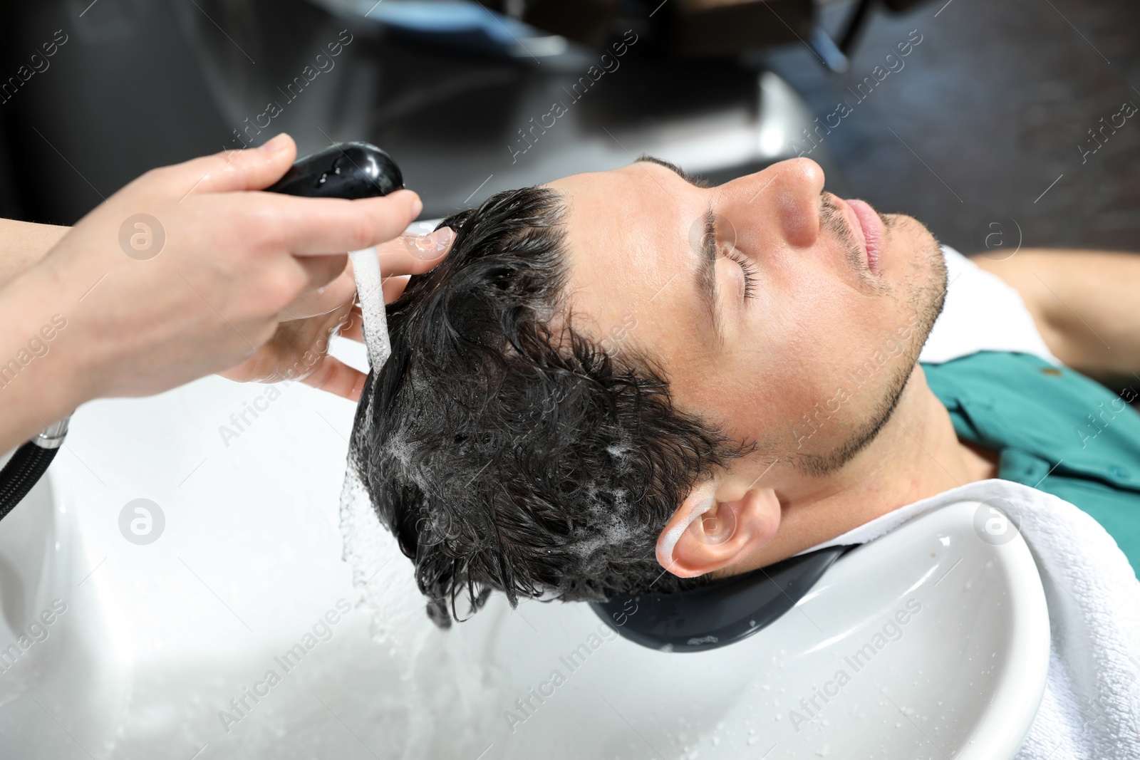 Photo of Stylist washing client's hair at sink in beauty salon