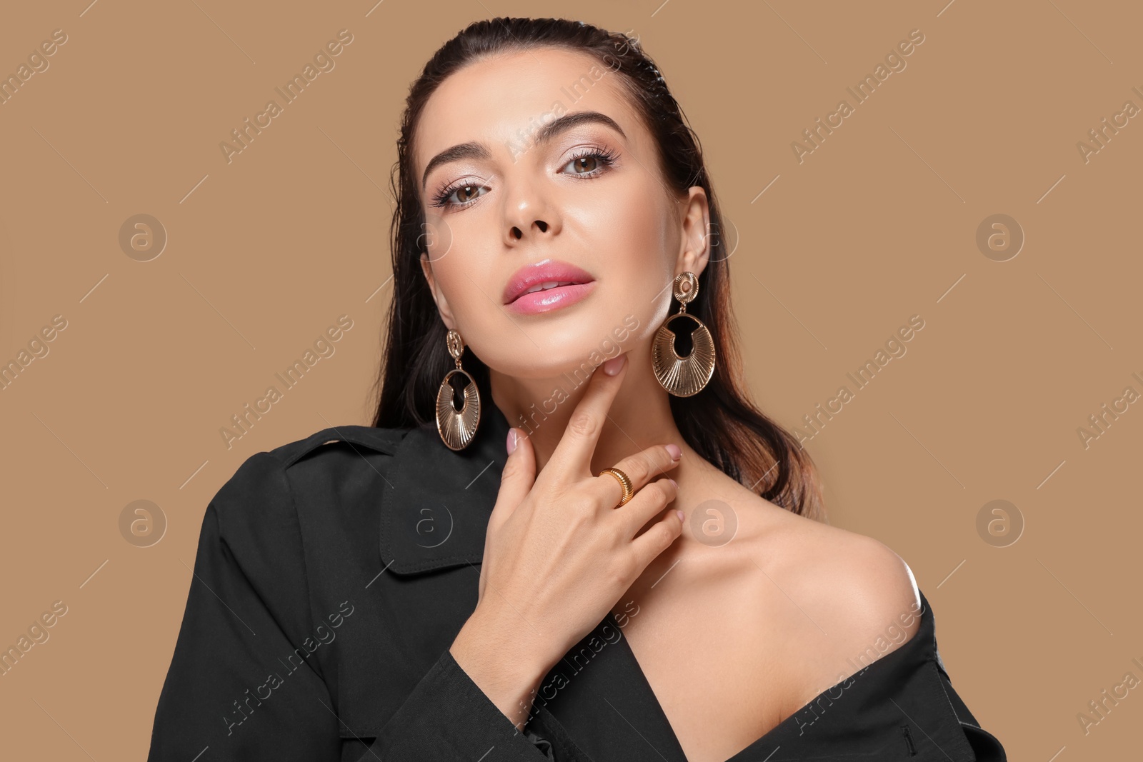 Photo of Portrait of young woman with beautiful makeup on light brown background