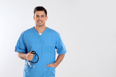 Doctor with stethoscope on light grey background. Space for text