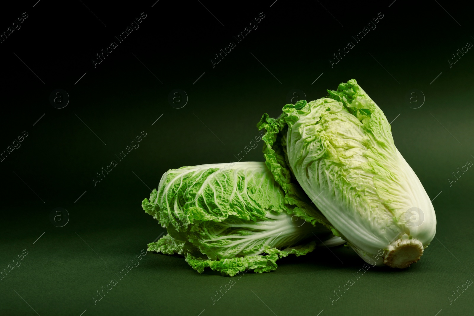 Photo of Fresh ripe Chinese cabbages on green background, space for text