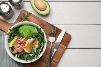 Delicious salad with boiled egg, salmon and avocado served on white wooden table, flat lay. Space for text