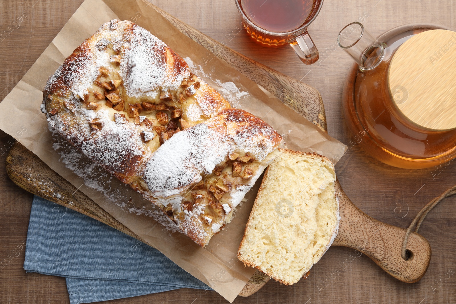 Photo of Delicious yeast dough cake and cup of tea on wooden table, flat lay