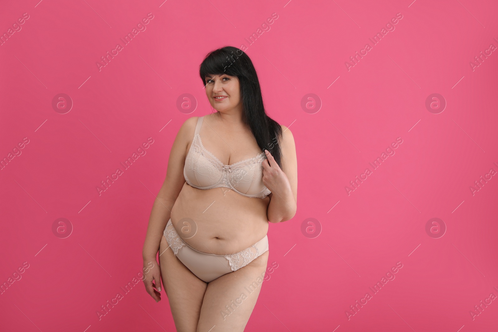 Photo of Beautiful overweight woman in beige underwear on pink background, space for text. Plus-size model