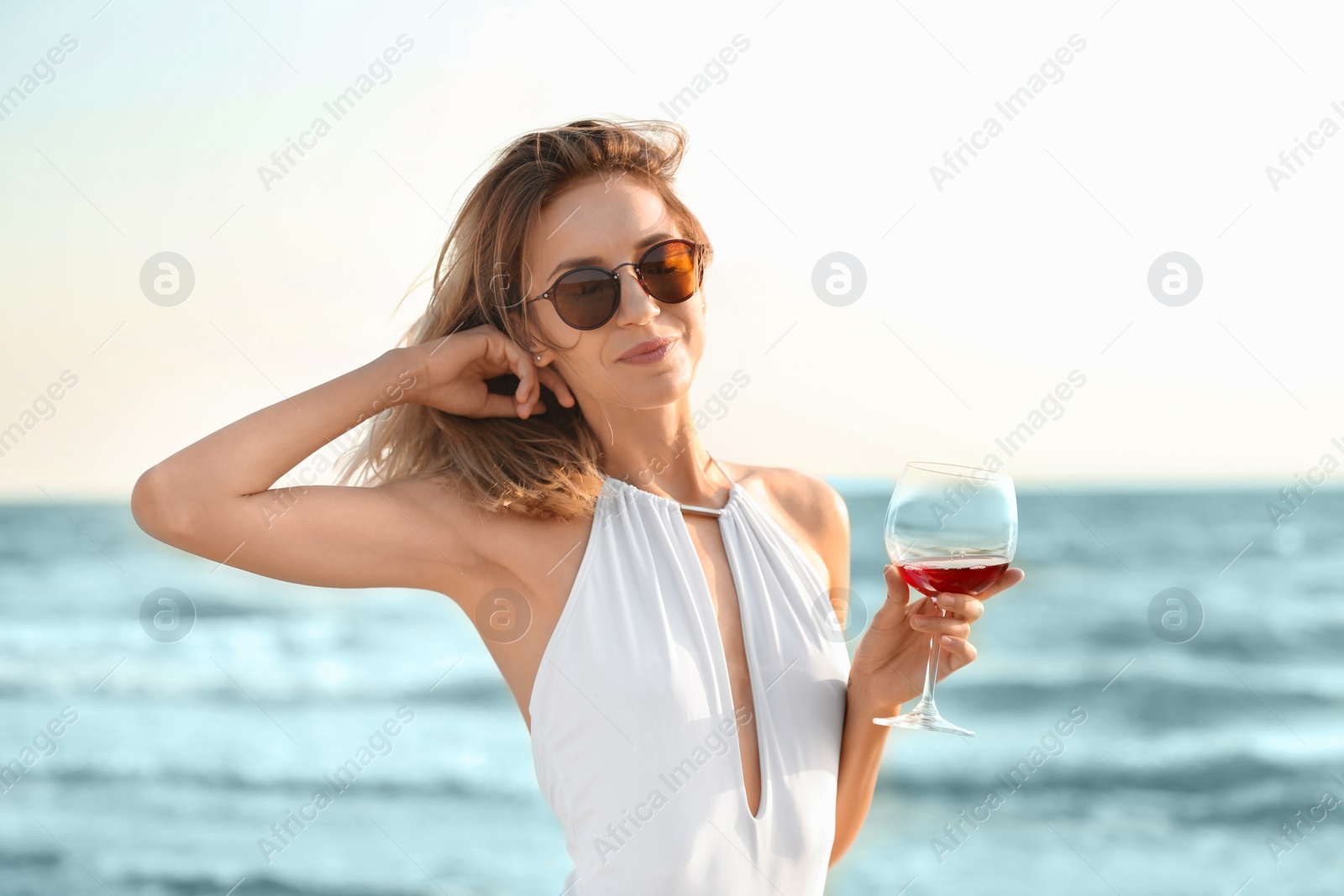 Photo of Young woman with glass of wine on beach