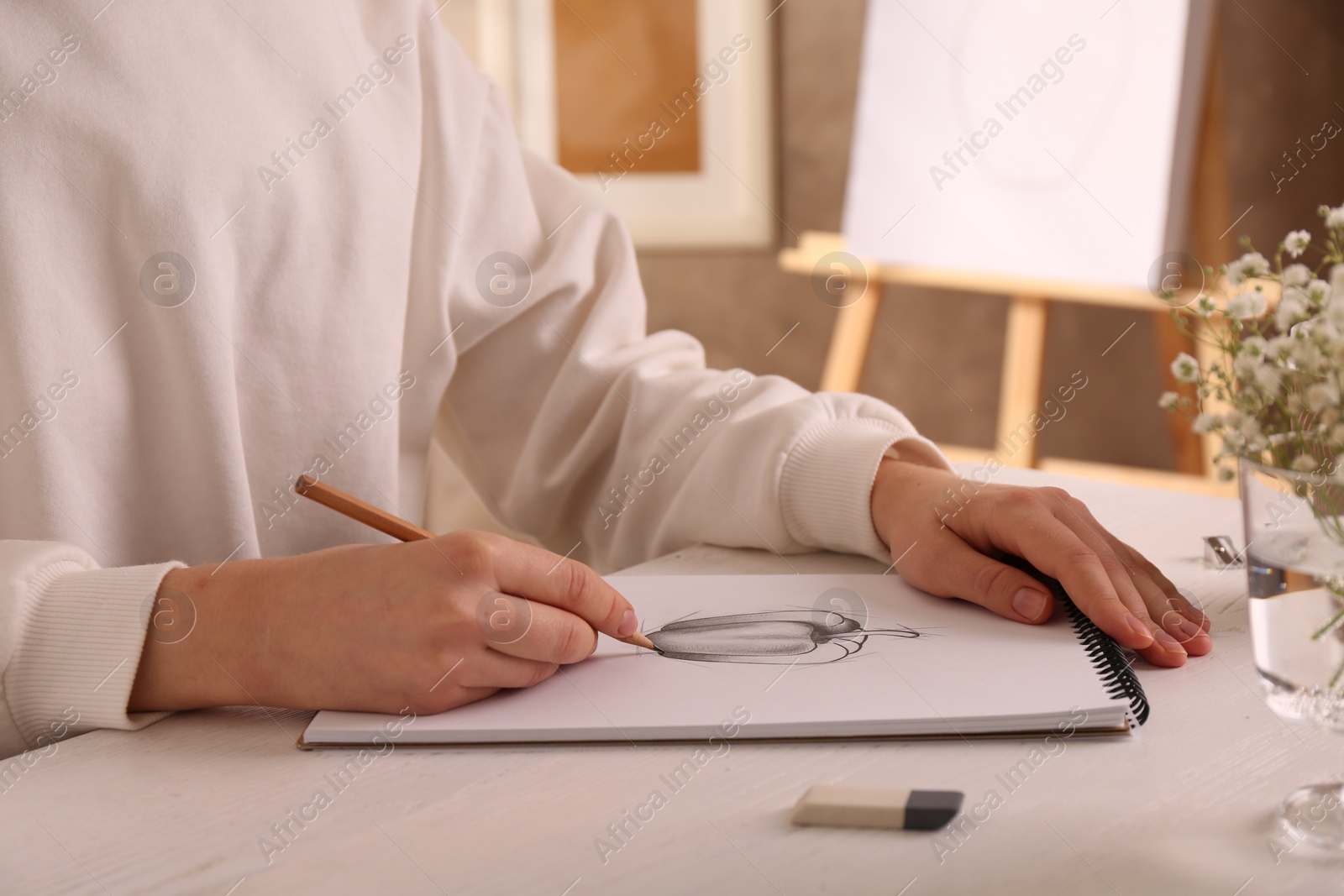 Photo of Woman drawing bell pepper with graphite pencil in sketchbook at table, closeup