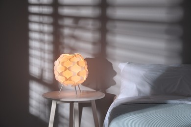 Photo of Stylish night lamp on bedside table in bedroom