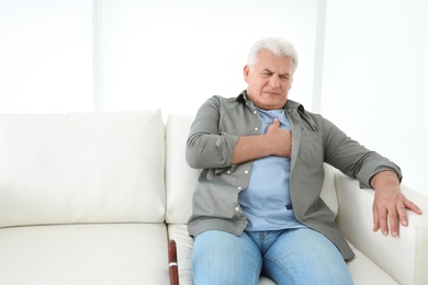 Photo of Senior man having heart attack on sofa
