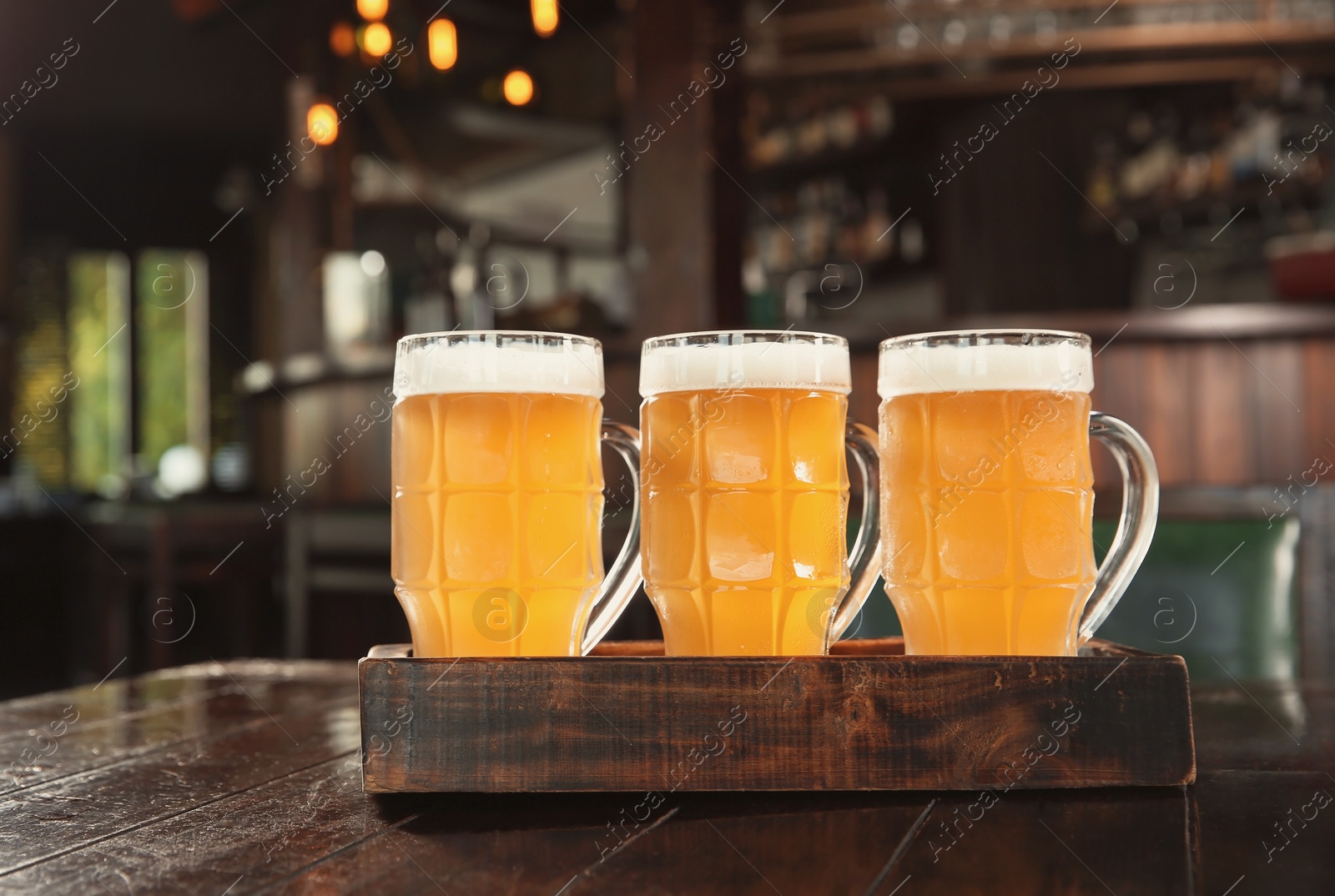 Photo of Glasses of tasty beer on wooden table in bar