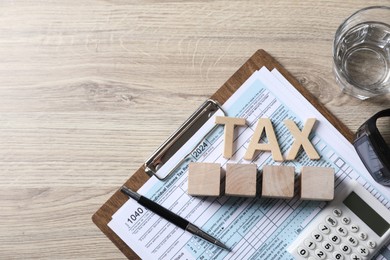 Word Tax, cubes, calculator, pen and document on wooden table, top view. Space for text