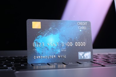 Photo of One plastic credit card on laptop, closeup