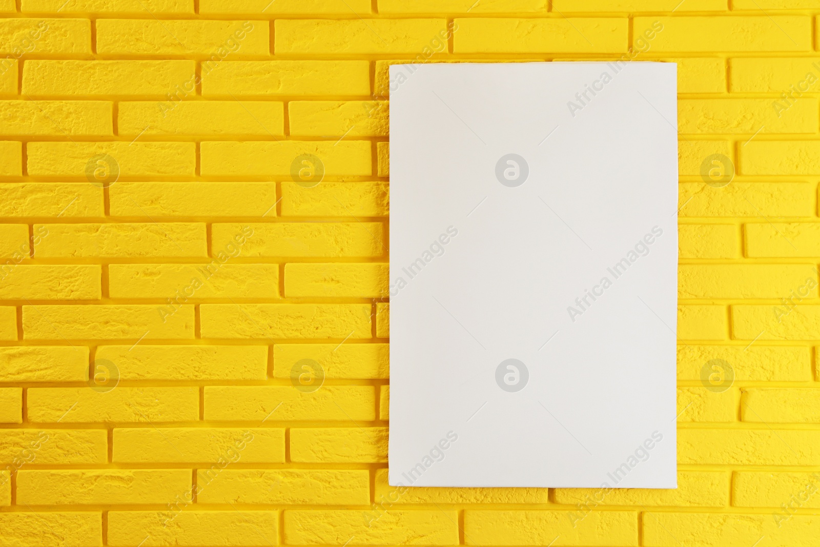 Photo of Blank canvas on yellow brick wall. Space for design