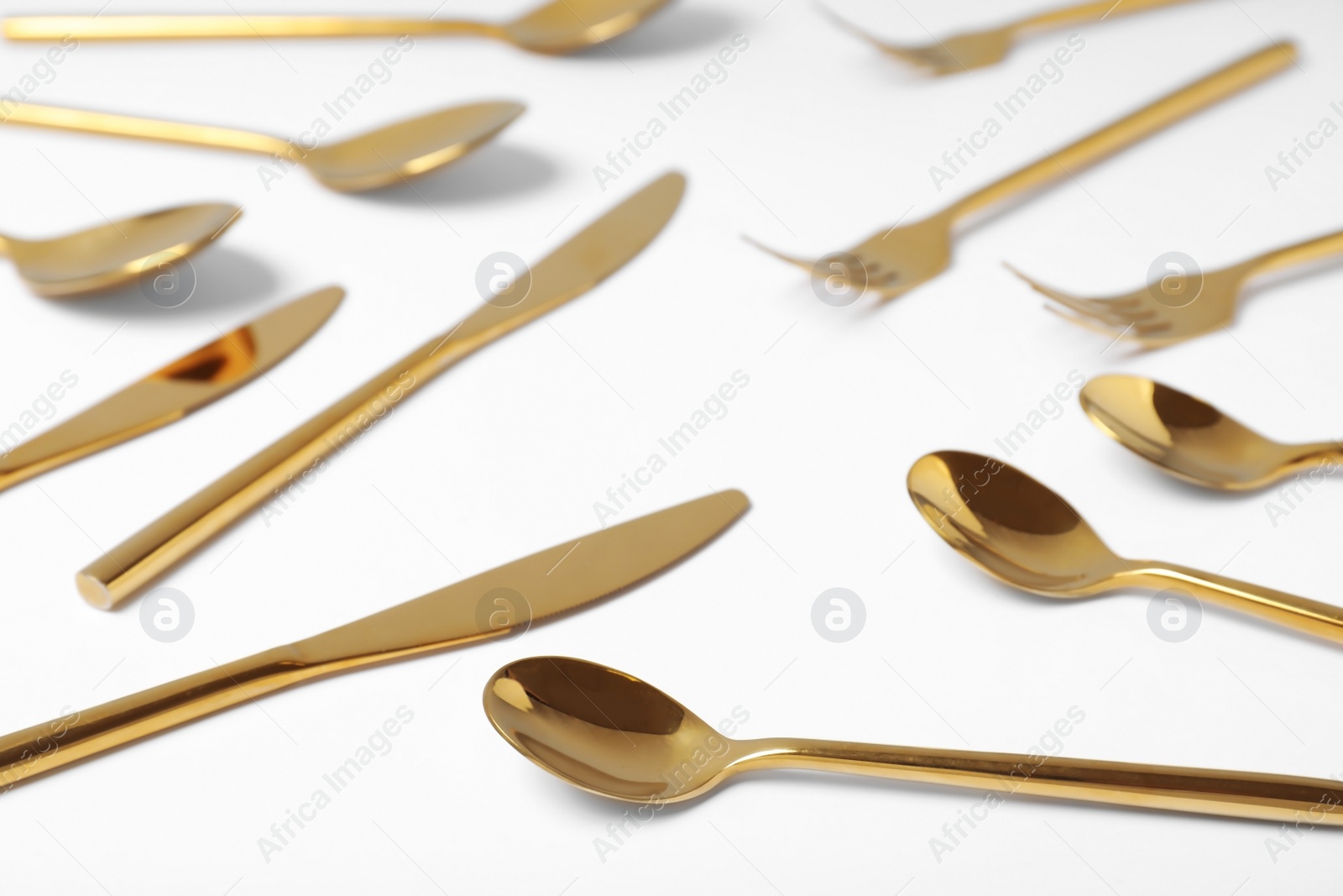Photo of Set of new gold cutlery on white background