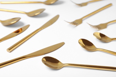 Set of new gold cutlery on white background