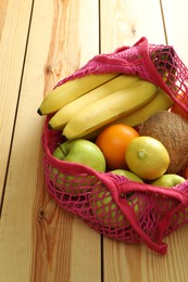 Photo of Net bag with fruits on wooden table