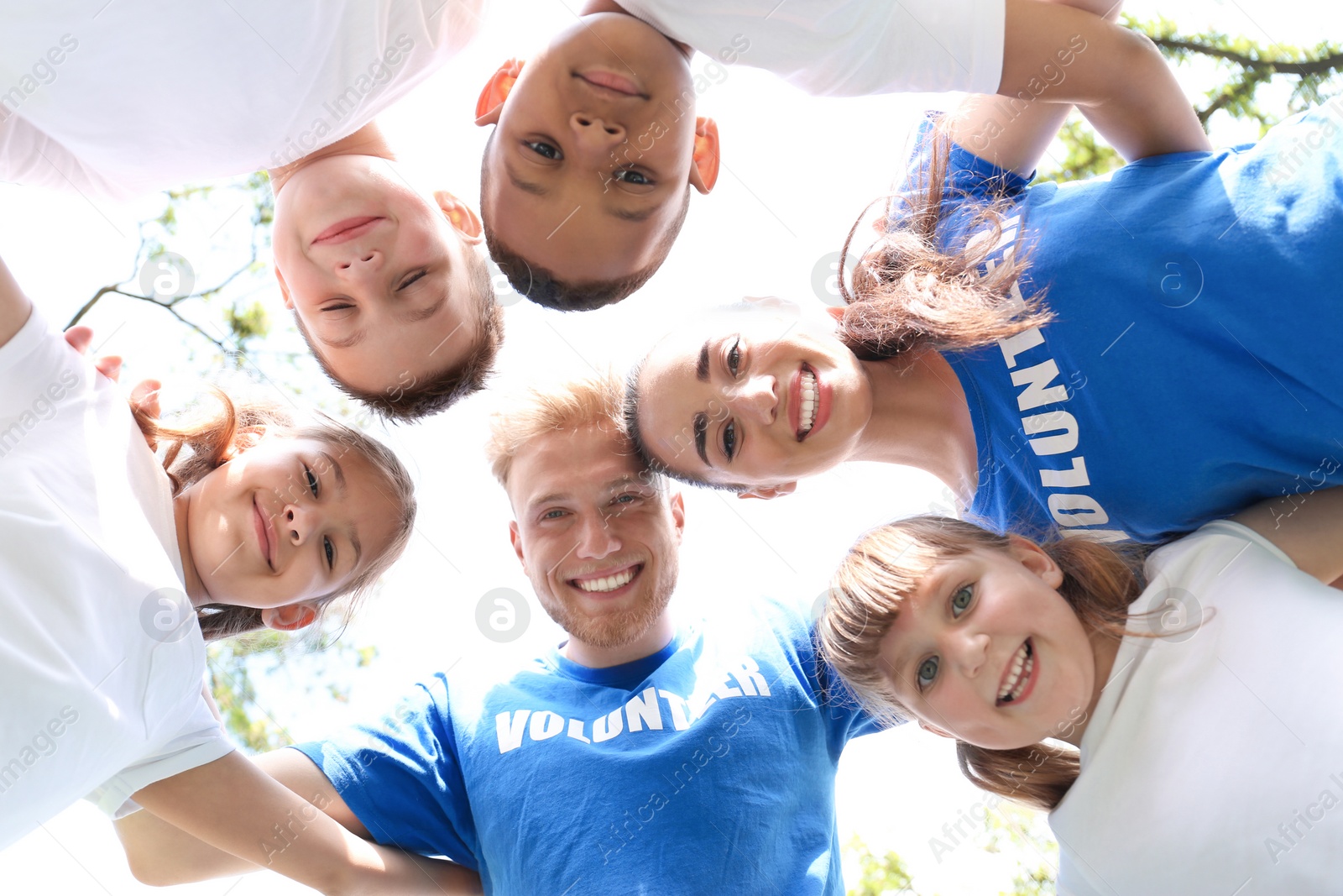 Photo of Low angle view of volunteers huddling with kids in park