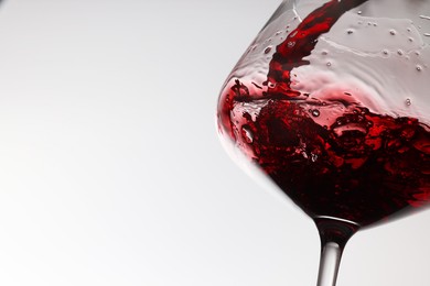 Photo of Tasty red wine in glass on white background, closeup. Space for text