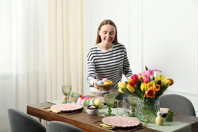 Photo of Woman setting table for festive Easter dinner at home