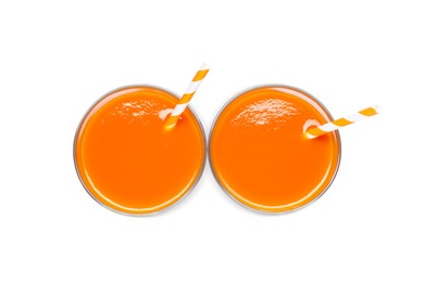 Two glasses of carrot juice with straws on white background, top view