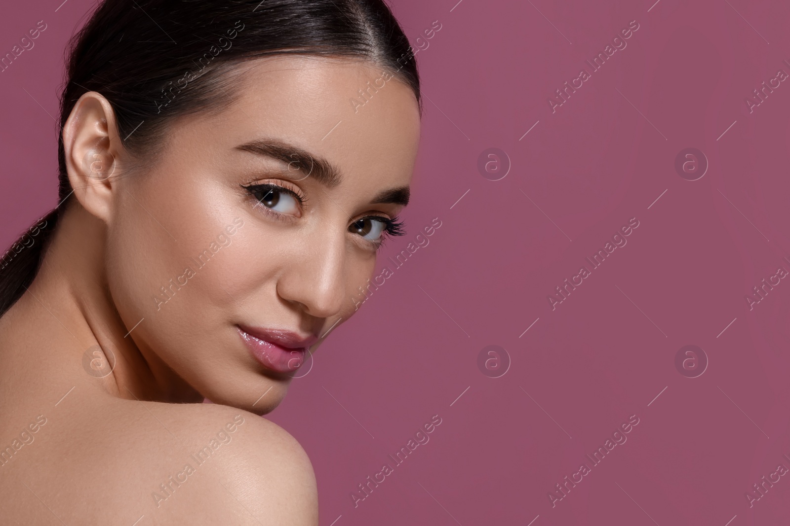 Photo of Portrait of beautiful young woman with perfect makeup on dark pink background. Space for text