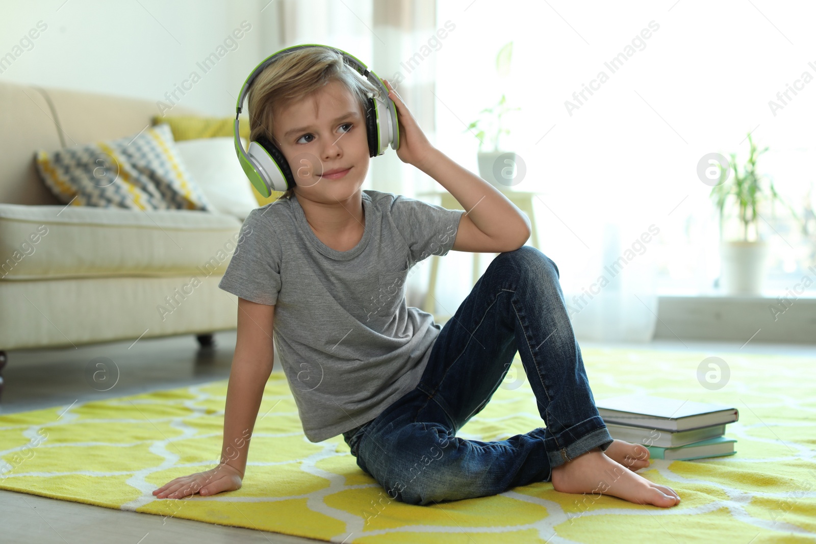 Photo of Cute little boy with headphones listening to audiobook at home