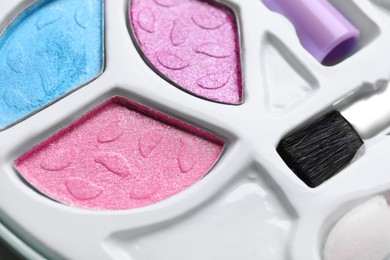 Photo of Decorative cosmetics for kids. Eye shadow palette with brush as background, closeup