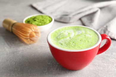 Photo of Cup of tasty matcha latte on light gray table, closeup