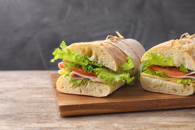 Photo of Tasty sandwiches with ham on wooden table, closeup