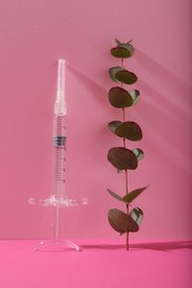 Photo of Cosmetology. Medical syringe and eucalyptus branch on pink background