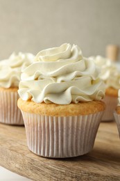 Tasty vanilla cupcakes with cream on table, closeup