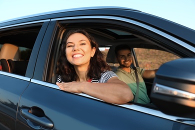 Happy young couple traveling by family car on summer day