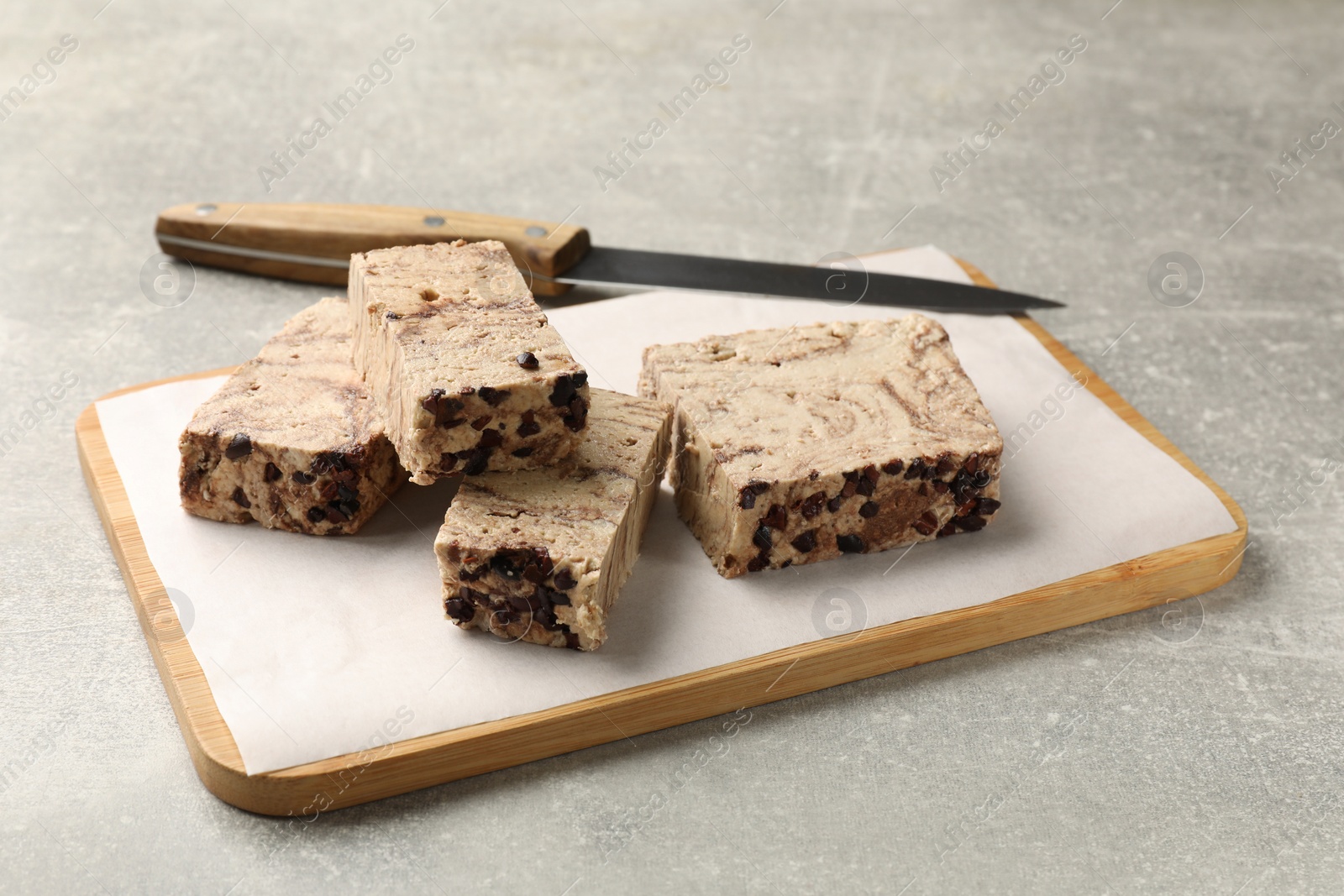 Photo of Tasty chocolate halva and knife on grey table