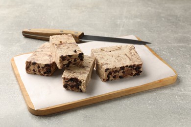 Photo of Tasty chocolate halva and knife on grey table