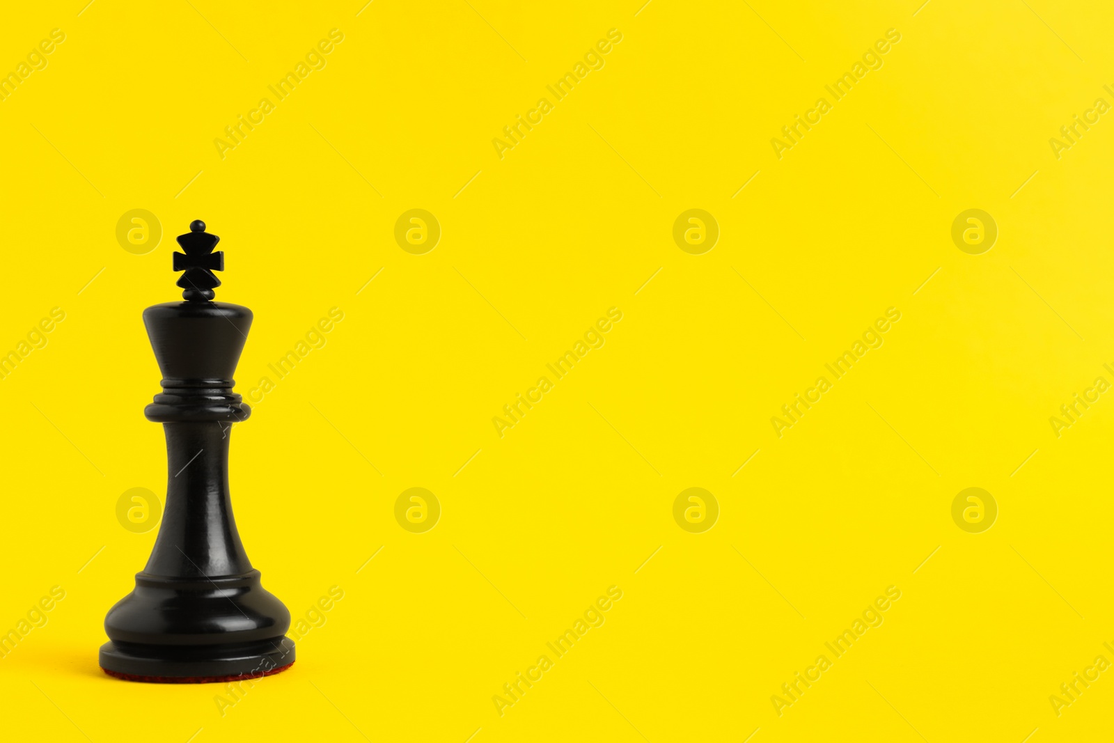 Photo of Black king on yellow background, space for text. Chess piece