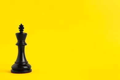 Photo of Black king on yellow background, space for text. Chess piece